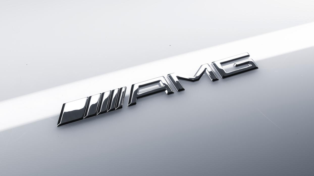 Das aktuelle AMG Logo in Metall auf weißem Autolack