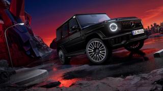 Mercedes-AMG G63 mit Two-Finish Paket in seitlicher Rückansicht auf schwarzer Fläche mit Felsen und Sonnenuntergang im Hintergrund