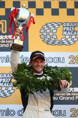 Maro Engel with the winner's crown raises the trophy in the air