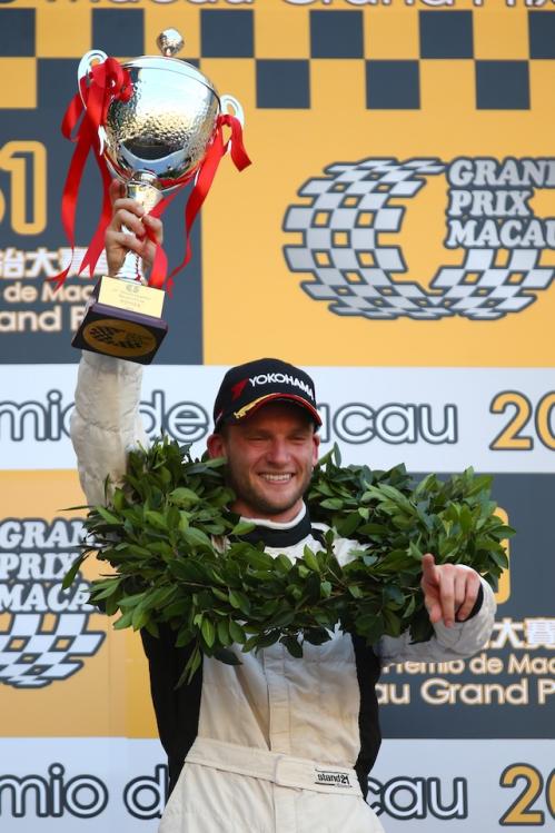 Maro Engel with the winner's crown raises the trophy in the air