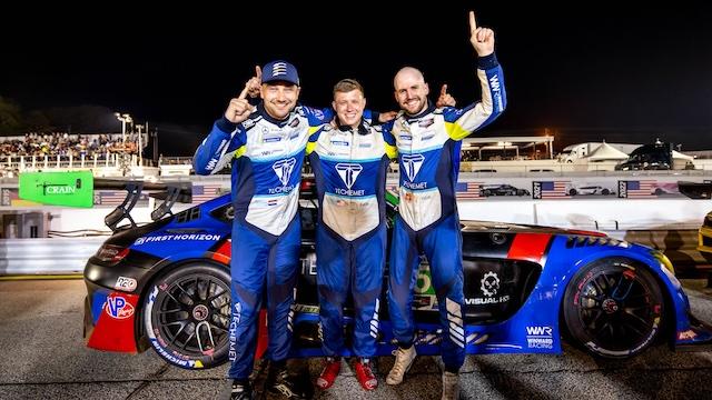 Three racing drivers stand in front of their Mercedes-AMG GT