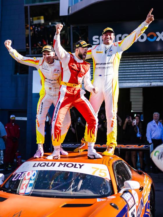 Three Mercedes-AMG GT drivers stand on a vehicle and celebrate