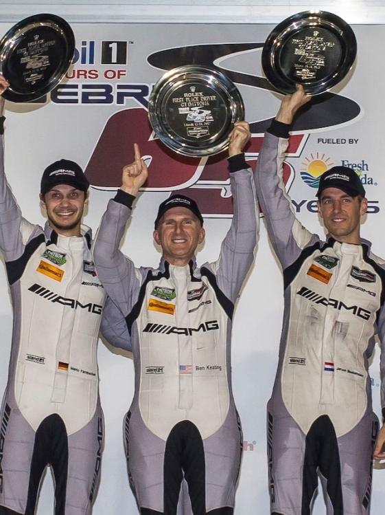 Three Mercedes-AMG racing drivers raise their shells into the air