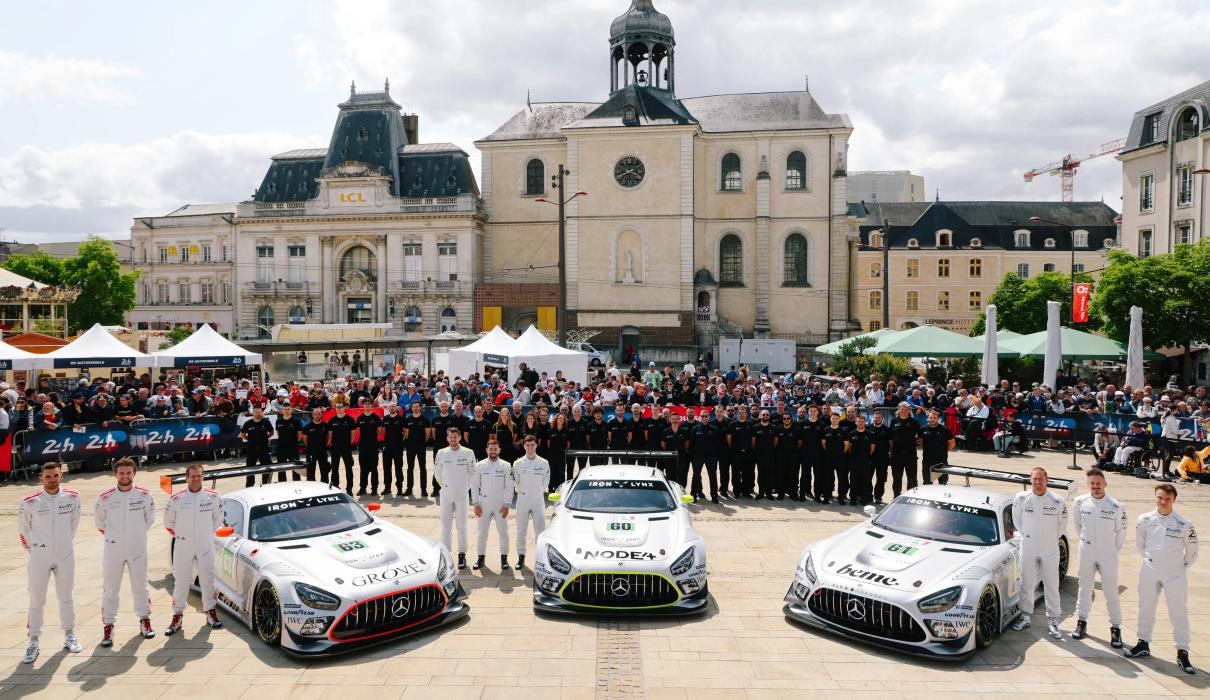 Mercedes-AMG GT teams pose for a photo on a market square