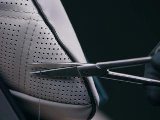 Der Garn eines MANUFAKTUR Kissens wird mit einer Schere abgeschnitten.