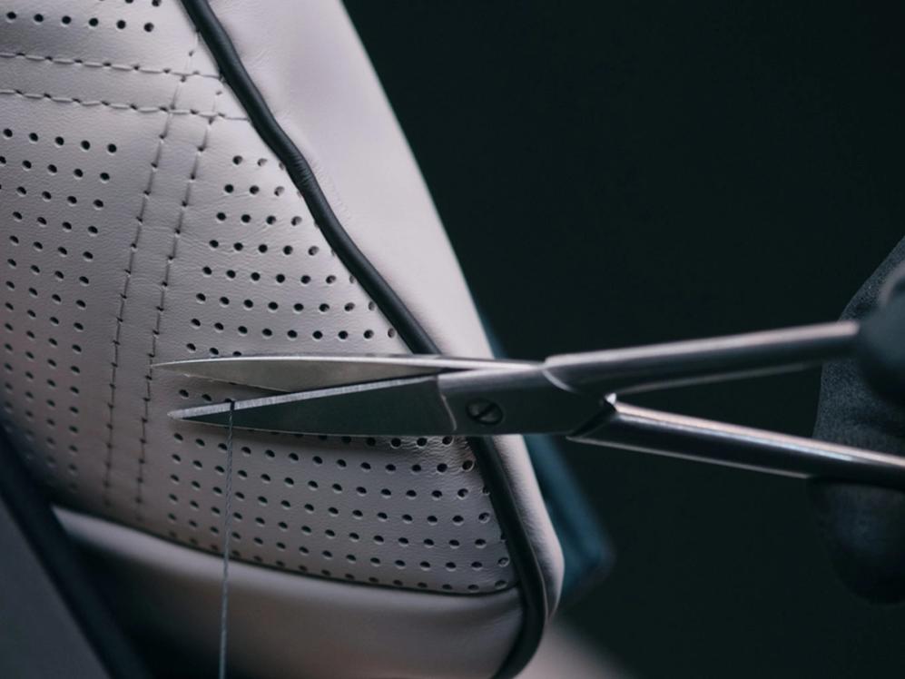 Der Garn eines MANUFAKTUR Kissens wird mit einer Schere abgeschnitten.