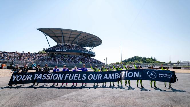 Vier Mercedes-AMG GT Teammitglieder halten ein Banner mit "Your passion fuels our ambition"